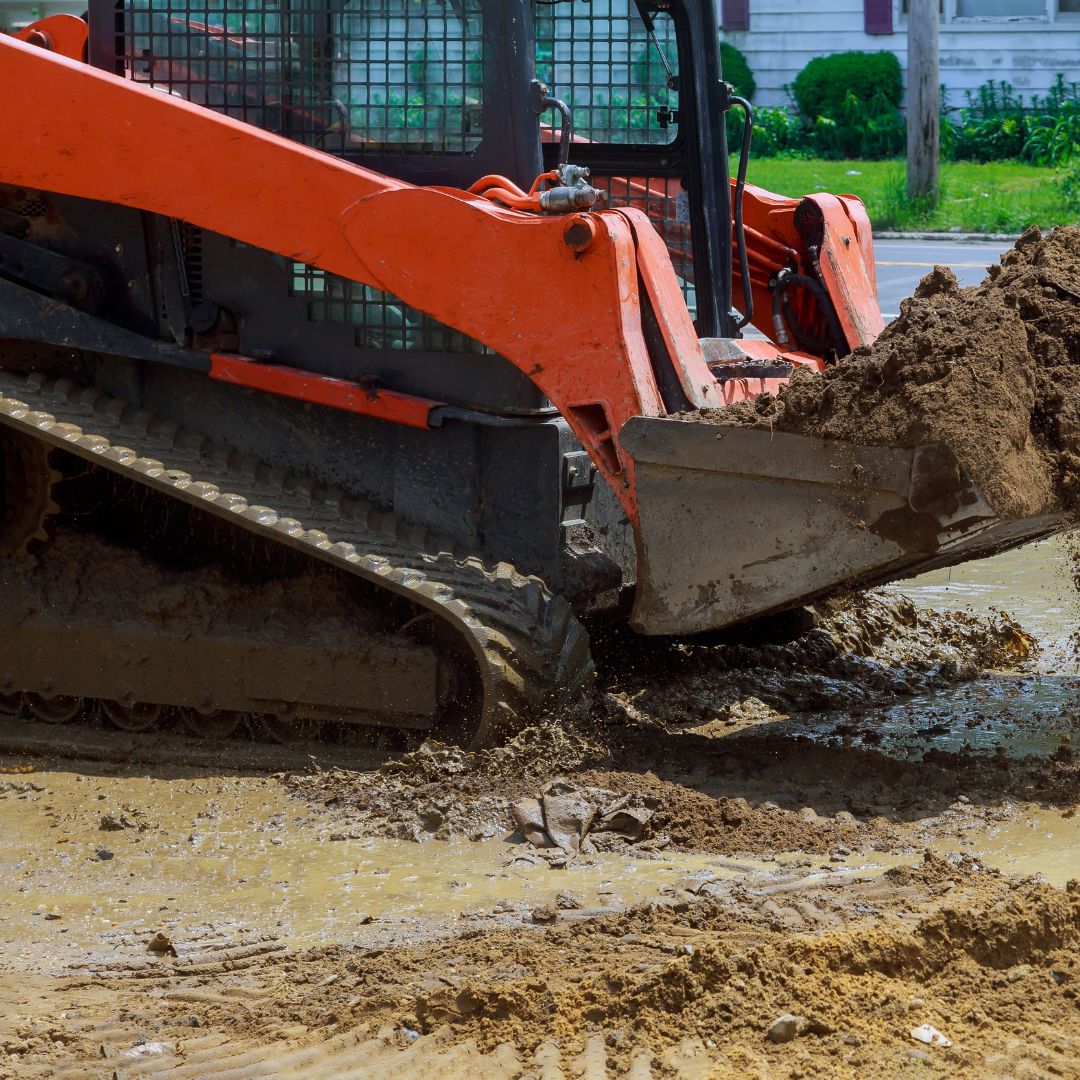 Machinery with rubber tracks lifting dirt